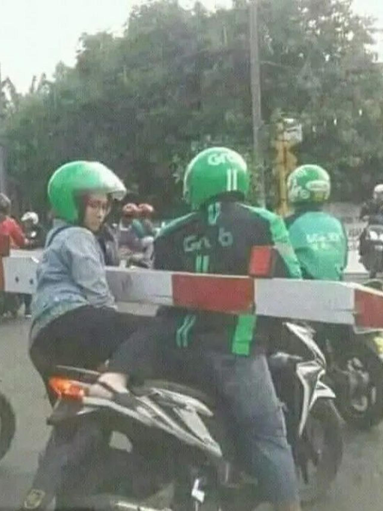 Ojol terpisahkan oleh palang pintu kereta api (Facebook/Komite Humor Online) 