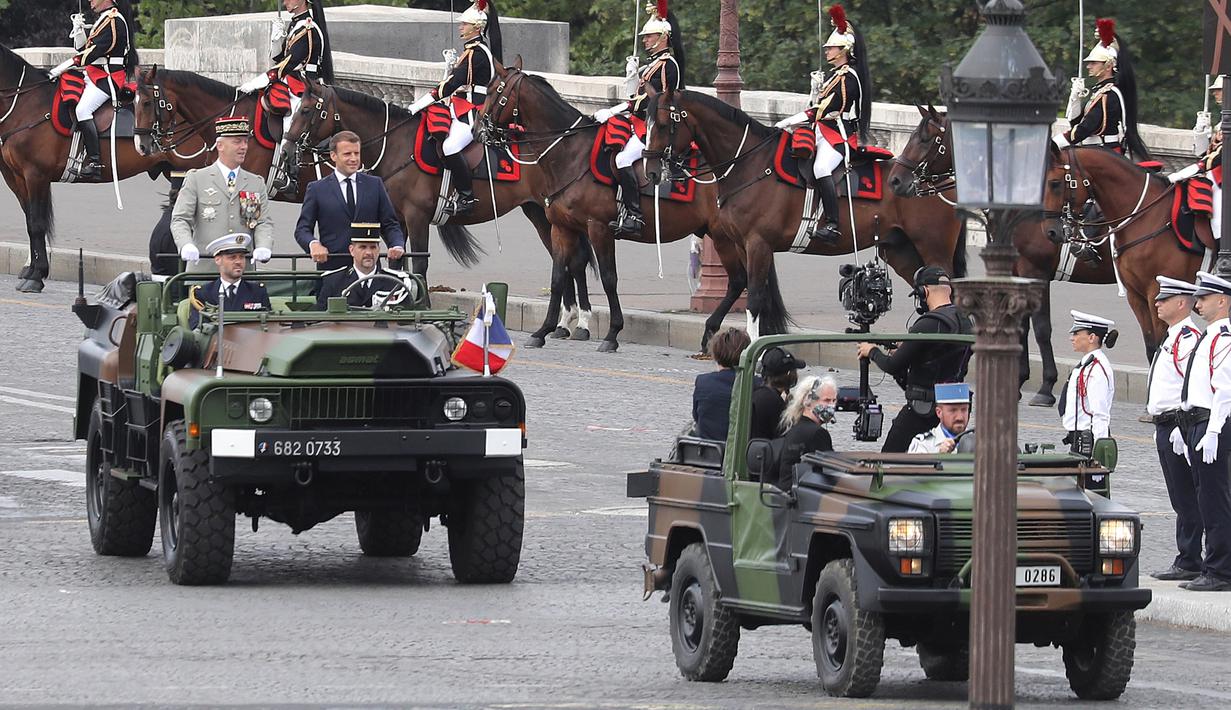 Presiden Prancis Emmanuel Macron (kanan) tiba dengan Kepala Staf Pertahanan Jenderal Francois Lecointre dalam upacara militer Bastille Day di Place de la Concorde di Paris, Prancis (14/7/2020). (AFP/Thomas Samson)