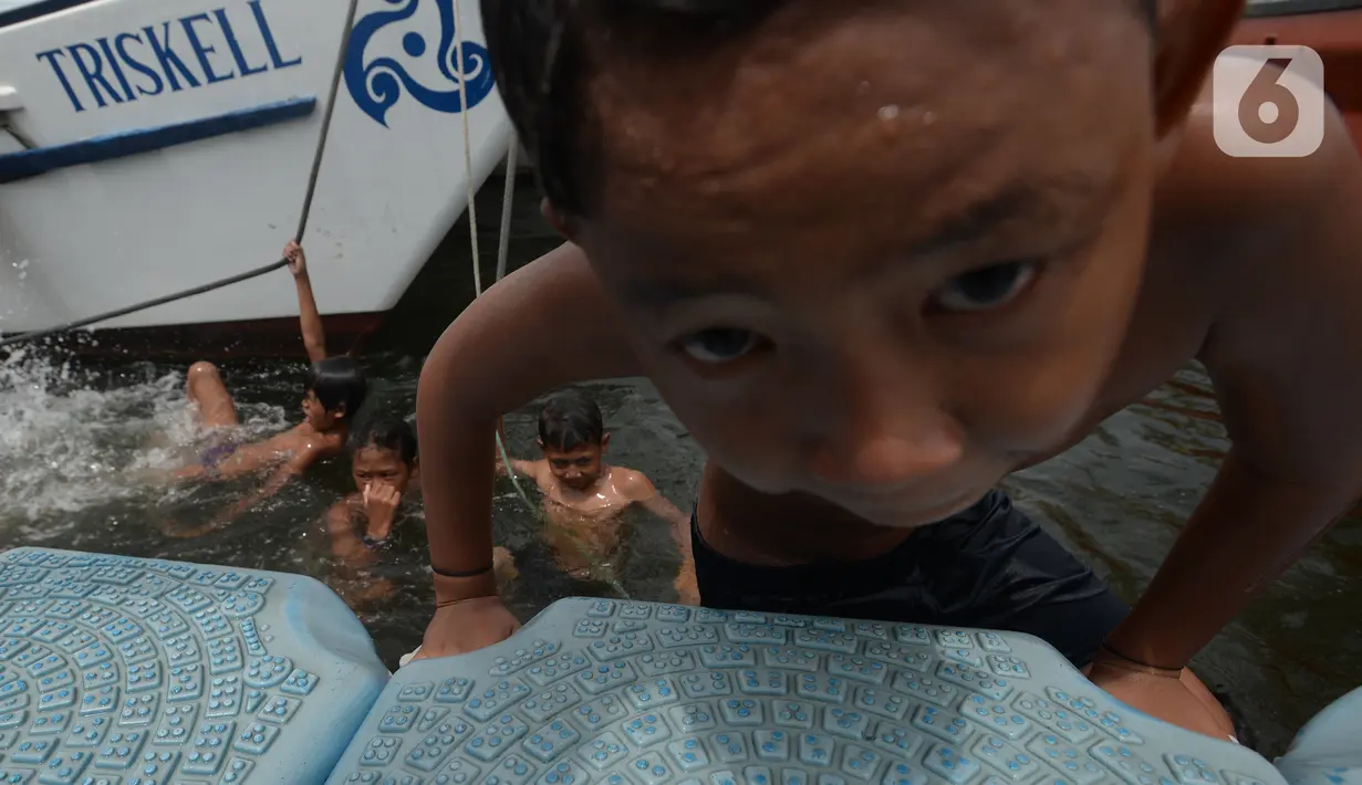 Anak-anak bermain di kawasan Muara Angke, Jakarta, Sabtu (10/4/2021). Lahan tepi dermaga Kali Adem dimanfaatkan bagi anak-anak pesisir untuk bermain di area kapal bersandar. (merdeka.com/Imam Buhori)