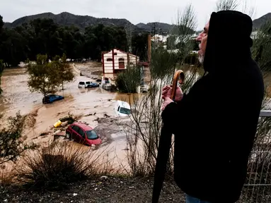 Seorang pria mengamati beberapa mobil yang tersapu air di kota Alora, Malaga, Spanyol, Selasa, 29 Oktober 2024. (AP Photo/Gregorio Marrero)