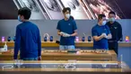 Para pekerja mengenakan masker saat menjaga Apple Store yang dibuka kembali di Beijing, China, Jumat (14/2/2020). Apple kembali membuka tokonya di China setelah pada awal Februari lalu menutup seluruhnya karena khawatir terhadap wabah virus corona. (AP Photo/Mark Schiefelbein)