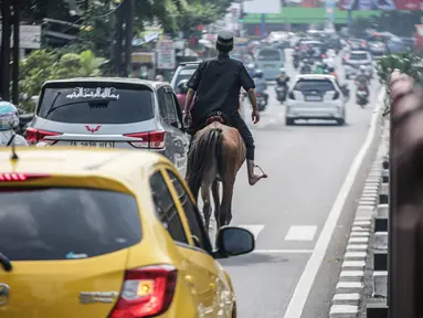 Seorang pria terlihat menunggangi kuda usai melaksanakan sholat Jumat di kawasan Jalan Raya Kramat Jati, Jakarta, Jumat (23/6/2023). (Liputan6.com/Faizal Fanani)