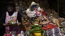 Seorang perempuan menjual barang-barang miniatur di samping patung Ekeko, Dewa Kemakmuran, pada hari pembukaan Pameran tahunan Alasita, di mana Ekeko adalah tokoh utamanya di El Alto, Bolivia, Selasa (24/1/2023). Orang-orang membeli replika kecil dari hal-hal yang ingin mereka peroleh sepanjang tahun, seperti rumah, mobil, dan kekayaan. Kata Aymara "Alasita" berarti "belikan aku". (AP Photo/Juan Karita)