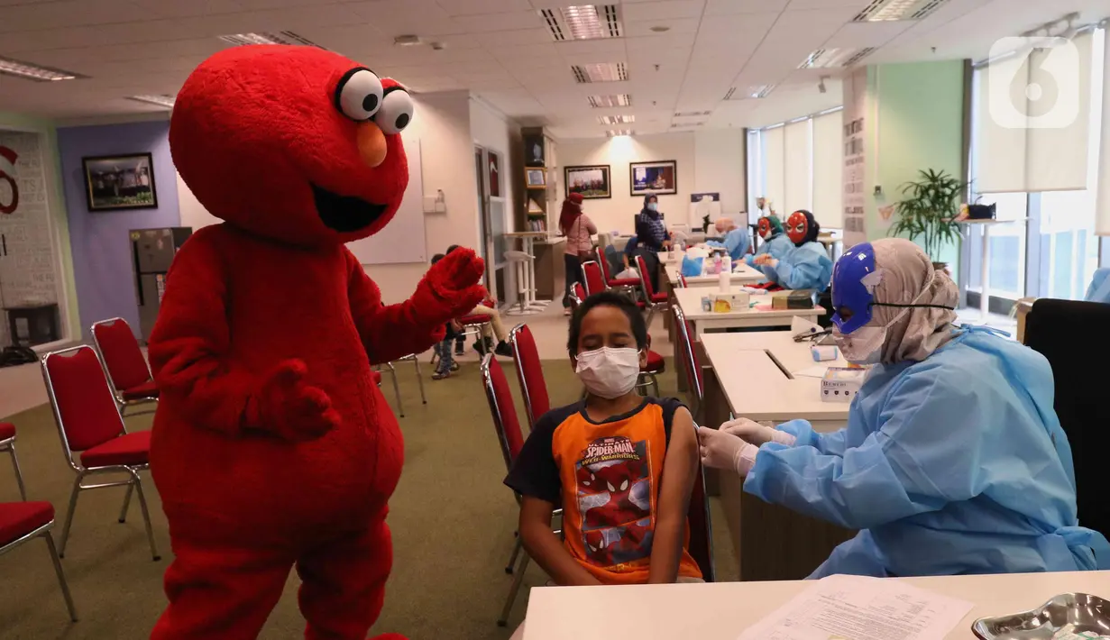 Petugas medis dengan mengenakan topeng superhero menyuntikkan vaksin Sinonvac kepada anak-anak saat mengikuti vaksinasi kedua di Gedung  Otoritas Jasa Keuangan (OJK), Jakarta, Minggu (16/01/2022). (Liputan6.com/Angga Yuniar)