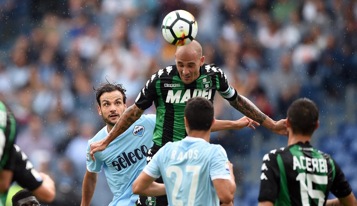 Pemain Lazio, Marco Parolo (kiri) mencoba mengganggu sundulan pemain Sassuolo, Paolo Cannavaro pada lanjutan Serie A di Olympic Stadium, Roma, (1/10/2017). Lazio menang telak 6-1. (AFP/Filippo Monteforte)