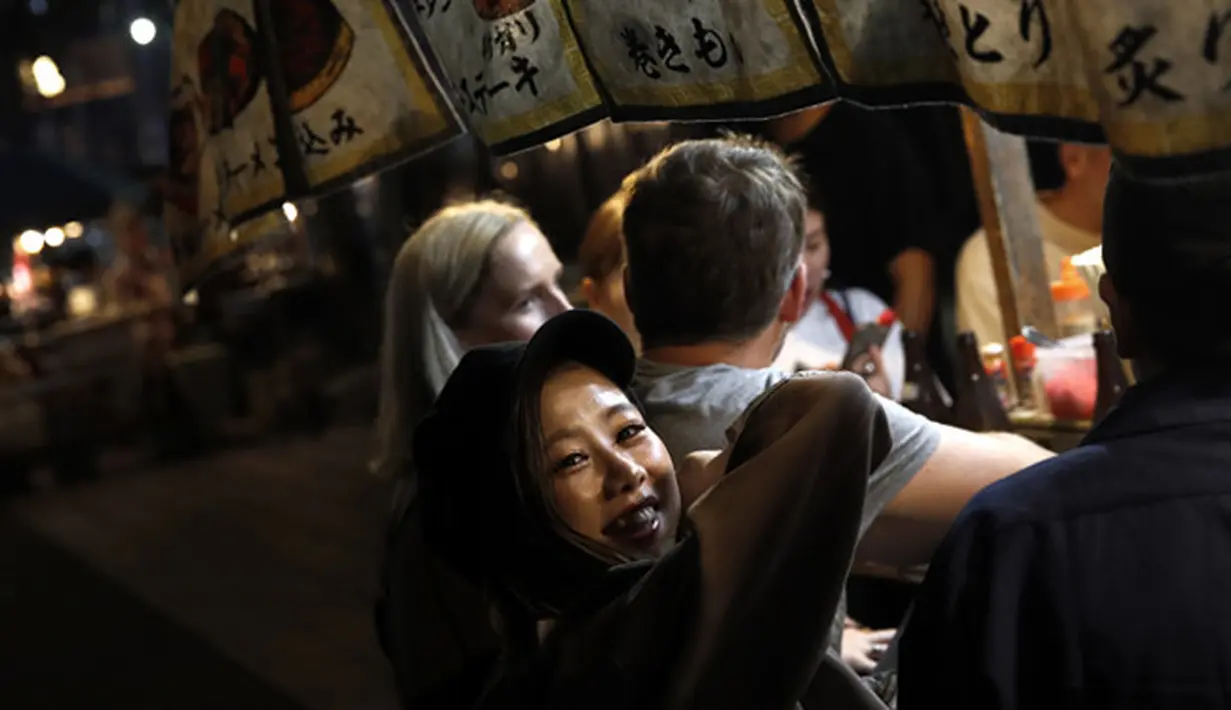 Seorang wanita tersenyum di stan makanan terbuka (Yatai) di Fukuoka, Jepang barat daya 1/10/2019). Yatai menyediakan lingkungan luar ruangan yang nyaman untuk menikmati berbagai makanan yang umumnya sederhana dan mengenyangkan. (AP Photo/Christophe Ena)