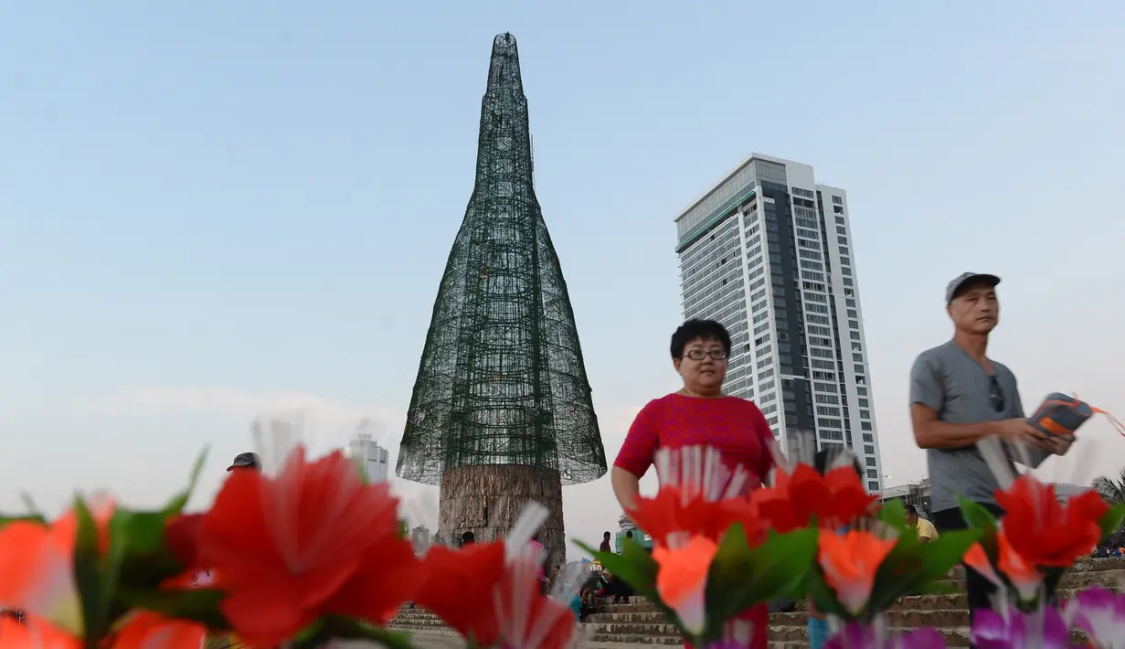 Pengunjung berpose dengan latar pohon Natal di Kolombo, Sri Lanka, Sabtu (24/12). Tingginya yang mencapai 50 meter ini dinobatkan sebagai pohon natal tertinggi di dunia. (AFP PHOTO / Lakruwan Wanniarachchi)