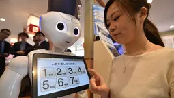 Seorang karyawati dari restoran sushi Hamazushi menguji coba robot humanoid Pepper saat press preview di Saitama, Jepang (2/2). Robot tersebut dapat melayani pelanggan dan membuka pintu masuk ke meja resepsionis. (AFP/Kazuhiro Nogi)