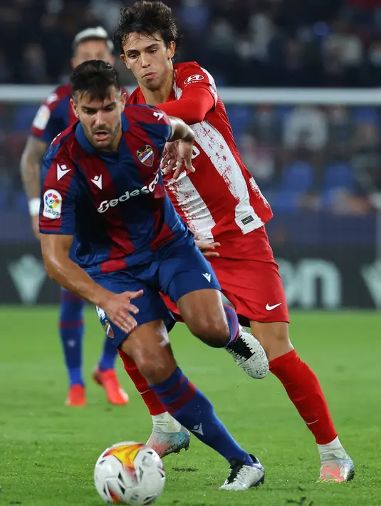 Bek Levante, Rober Pier (kiri) membawa bola dari kejaran gelandang Atletico Madrid, Joao Felix selama pertandingan La Liga Spanyol di stadion Ciutat de Valencia di Valencia (29/10/2021). Atletico kini menempati di urutan keenam klasemen sementara LaLiga dengan 19 poin. (AFP/Jose Jordan)
