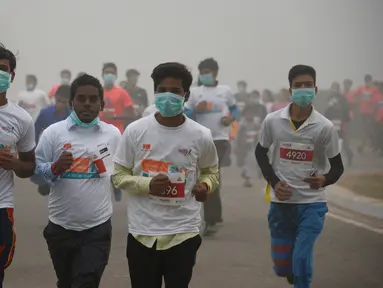 Peserta lari New Delhi 10K menggunakan masker tetap mengikuti lomba ditengah-tengah kabut polusi yang menimpa kota New Delhi, India (6/11). Kabut asap ini diklaim sebagai kabut terparah yang dialami oleh New Delhi dalam 17 tahun. (AFP/Dominique Faget)