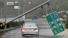 Mobil melewati papan penunjuk jalan yang ambruk akibat hantaman topan super Meranti di  Taiwan selatan, Rabu (14/9). Sejumlah kerusakan, seperti tiang listrik roboh dan banyaknya pohon tumbang dilaporkan terjadi akibat terjangan topan itu. (Sam YEH/AFP)