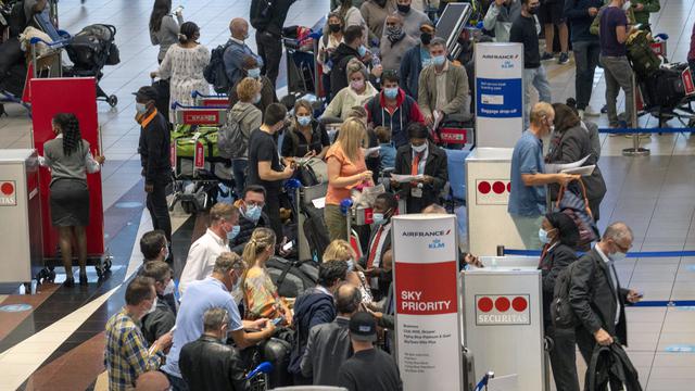 Orang-orang antre untuk naik penerbangan Air France menuju Paris di Bandara Internasional OR Tambo di Johannesburg, Jumat (26/11/2021). Sejumlah negara menghentikan perjalanan udara dari Afrika Selatan terkait kemunculan varian baru COVID-19 yang berpotensi lebih menular di Afsel. (AP/Jerome Delay)