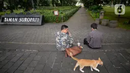 Warga sedang duduk diluar pembatas tulisan tanda ditutup sementara untuk mencegah penyebaran virus Covid-19 di Taman Suropati, Menteng, Jakarta, Senin (21/12/2020). (merdeka.com/Dwi Narwoko)