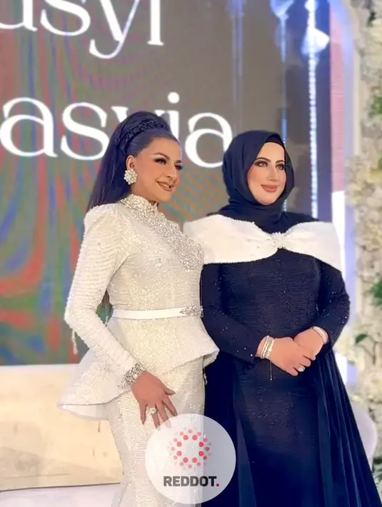 Sementara itu, Tasyi tampil dramatis dengan  gaun hitam yang dihiasi aksen pita besar warna putih di bagian bahu-nya. Penampilannya dilengkapi dengan hijab hitam. [@reddot.livestream].