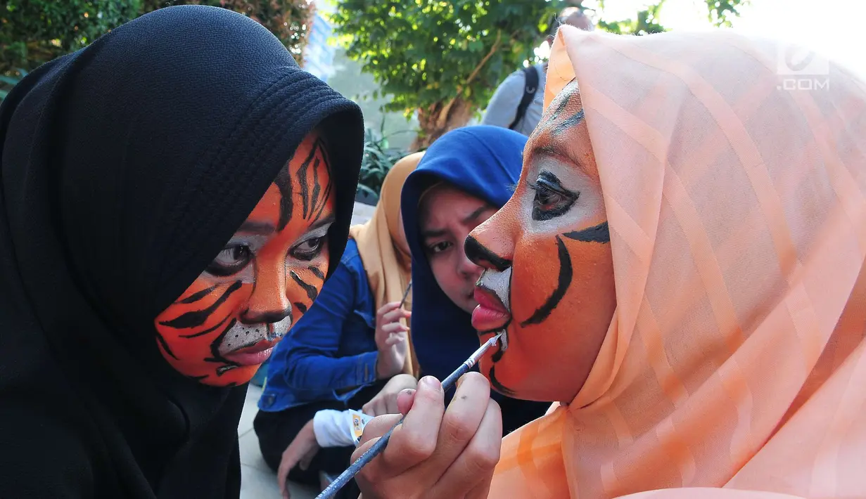 Peserta aksi dari forum harimaukita berdandan sebelum melakukan aksi teatrikal di Bundaran HI, Jakarta, Minggu (30/7). Acara ini diharapkan mampu meningkatkan minat masyarakat untuk terlibat dalam melestarikan habitat harimau.  (Liputan6.com/Helmi Afandi)