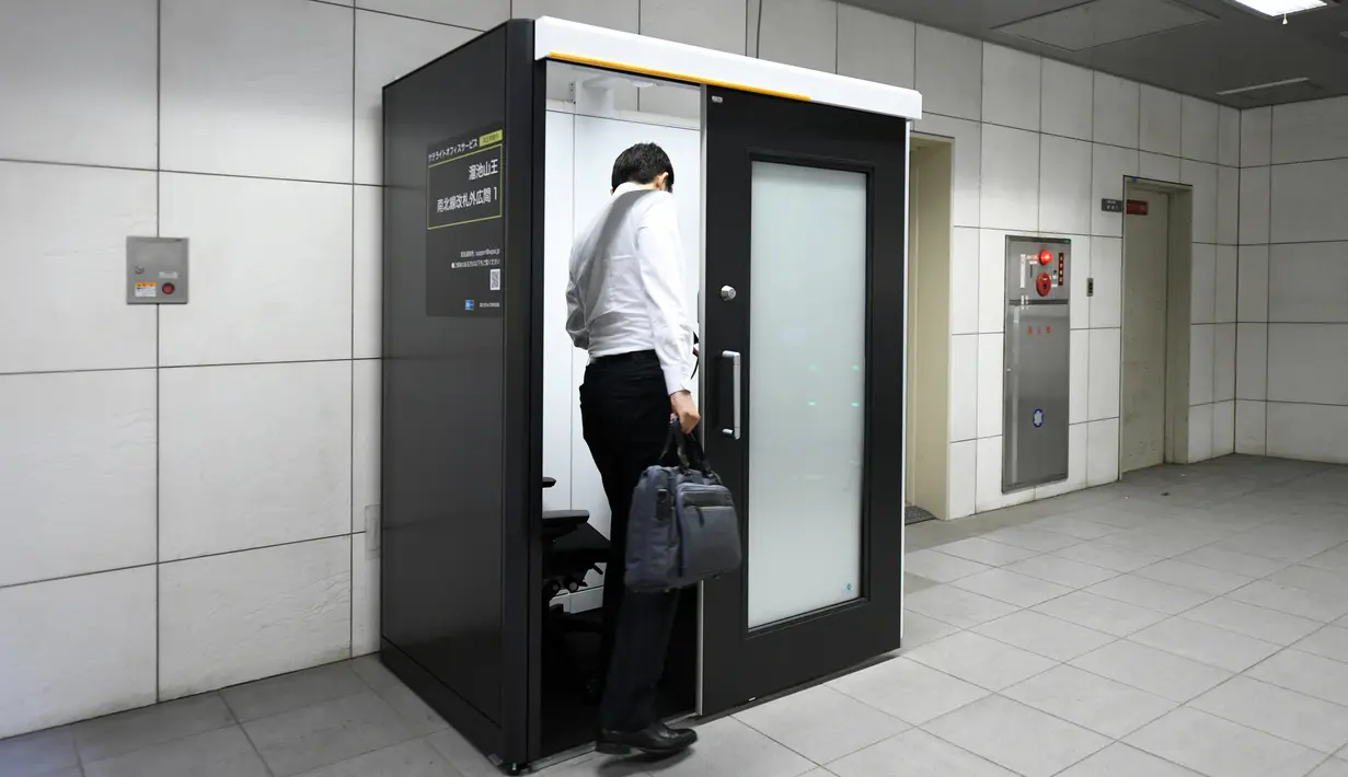 Foto 3 Juli 2018, karyawan Fuji Xerox masuk untuk bekerja di sebuah bilik yang dipasang di stasiun kereta bawah tanah Tokyo. Bilik itu dilengkapi meja dan kursi serta tampilan komputer dan wifi yang dapat dipesan secara online. (Toshifumi KITAMURA/AFP)