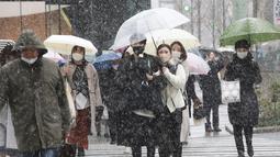 Orang-orang yang memakai masker untuk melindungi diri dari penyebaran virus corona berjalan di jalanan bersalju di Tokyo, Kamis (6/1/2022). Pusat Tokyo dan kota Tsukuba, Prefektur Ibaraki, mencatat 3 sentimeter salju, sementara Chiba dan Yokohama memiliki 2 cm salju. (AP Photo/Koji Sasahara)