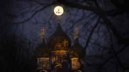 Supermoon terlihat di belakang salib dari gereja Ortodoks Kristen di Moskow, Rusia, Selasa (7/4/2020). Fenomena dimana bulan berada pada titik terdekat dengan bumi ini merupakan penampakan supermoon terbesar di tahun 2020. (AP Photo/Alexander Zemlianichenko)