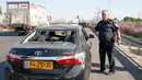 Polisi berdiri dekat mobil yang rusak dalam serangan roket dari Jalur Gaza di Kota Ashdod, Israel, Selasa (12/11/2019). Tewasnya komandan Jihad Islam Baha Abu Al-Ata memicu serangan balasan dari militan Palestina di Gaza. (Jack Guez/AFP)