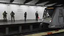 Penumpang berdiri di dekat petugas bersenjata saat menunggu kereta di Stasiun Metro Maelbeek di Brussels, Ibu Kota Belgia, Senin (25/4). Stasiun tersebut akhirnya dibuka kembali setelah serangan bom 22 Maret 2016 yang menewaskan 35 orang. (JOHN Thys/AFP)
