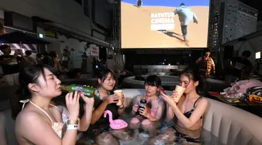 Pengunjung menikmati menonton film sambil berendam di Bathtub Cinema di atap gedung kawasan Shibuya, Tokyo, 17 Agustus 2018. Bathtub Cinema merupakan solusi kreatif yang ditawarkan oleh Afro&Co. untuk menikmati Tokyo di musim panas. (AFP/Kazuhiro NOGI)