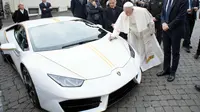 Paus Fransiskus memberikan tanda tangan di kap mesin Lamborghini Huracan di Vatikan, Rabu (15/11). Perusahaan Lamborghini memberi hadiah mobil Lamborghini Huracan berwarna putih untuk Paus Fransiskus. (L'Osservatore Romano/Pool Photo via AP)