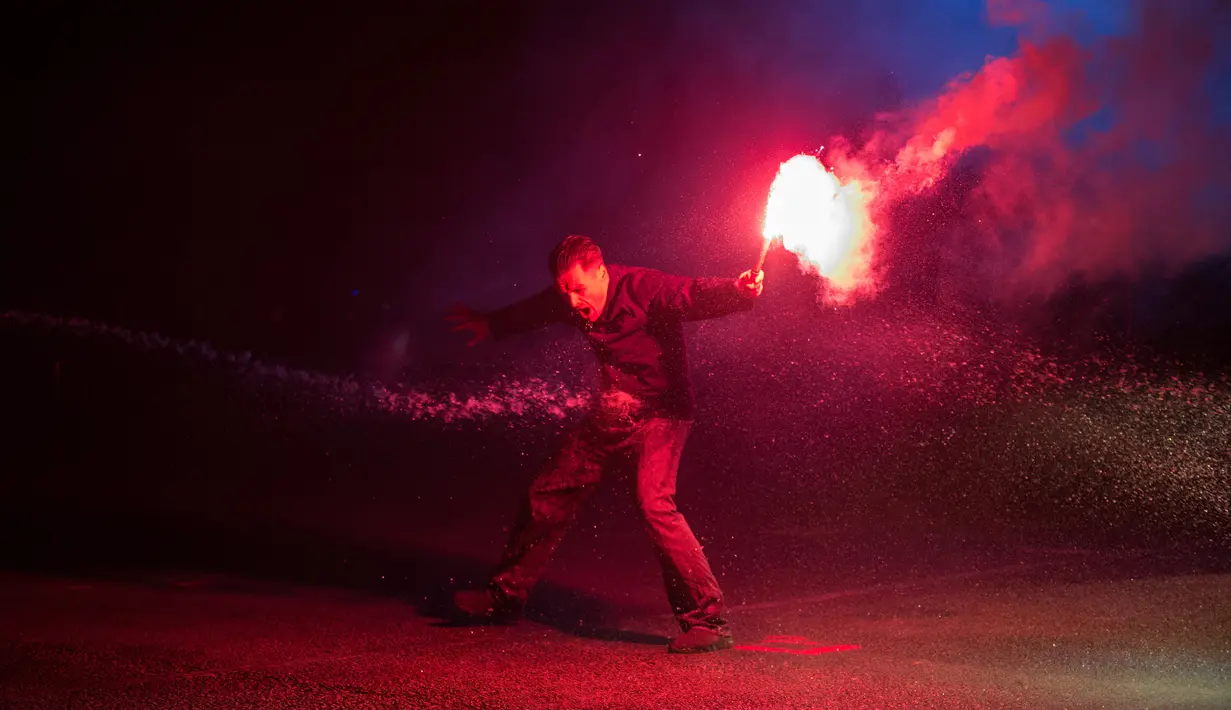 Seorang penari memegang suar selama pertunjukan 'RUSH', pertunjukan tari, cahaya, musik dan proyeksi dalam Festival Seni Visual Lightpool di situs bekas kantor polisi, Blackpool, Inggris (26/10). (AFP Photo/Oli Scarff)