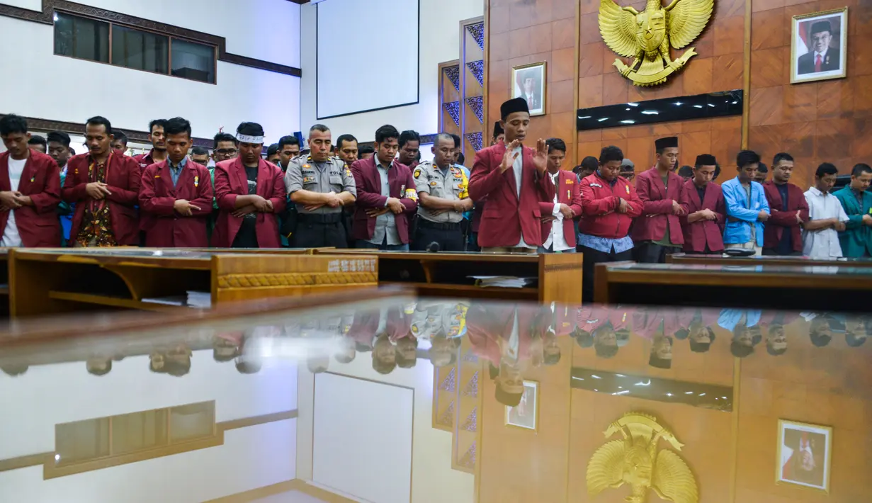 Mahasiswa dari berbagai perguruan tinggi bersama anggota kepolisian melaksanakan salat gaib di Gedung Dewan Perwakilan Rakyat Aceh (DPRA), Jumat (27/9/2019). Doa dan salat gaib itu untuk 2 mahasiswa Universitas Halu Oleo Kendari yang tewas saat demo, Randi dan Yusuf. (CHAIDEER MAHYUDDIN/AFP)