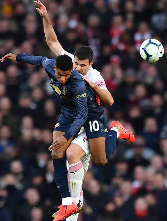 Striker Manchester United, Marcus Rashford berebut bola udara dengan bek Arsenal, Sokratis Papastathopoulos selama pertandingan lanjutan Liga Inggris di Stadion Emirates di London (10/3). Arsenal menang 2-0 atas MU. (AFP Photo/Ben Stansall)