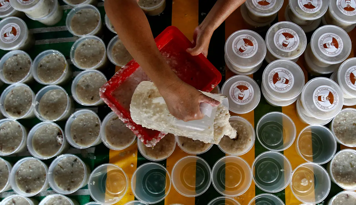 Proses penuangan Bubur Lambuk ke wadah yang telah disiapkan di desa Kampung Baru, Kuala Lumpur, Malaysia, Kamis (1/6).  Bubur Lambuk menjadi makanan khas Ramadan di Malaysia. (AP/Daniel Chan)