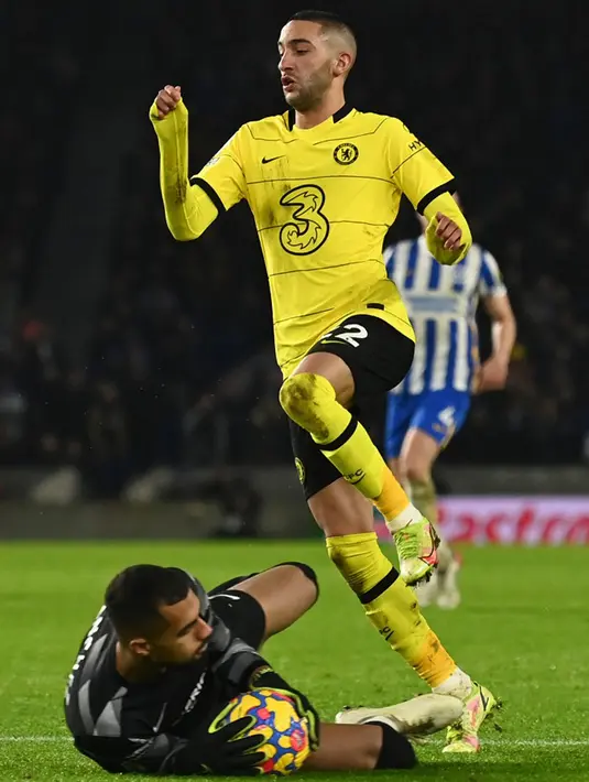 Penjaga gawang Brighton and Hove Albion Robert Sanchez (kiri) menyelamatkan bola dari pemain Chelsea Hakim Ziyech (kanan) pada pertandingan sepak bola Liga Inggris di American Express Community Stadium, Brighton, Inggris, 18 Januari 2022. Pertandingan berakhir 1-1. (Glyn KIRK/AFP)