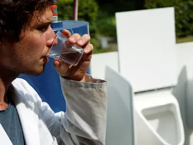 Ilmuwan Belgia, Sebastiaan Derese meminum air dari mesin buatannya yang bisa mengubah air seni menjadi air yang layak diminum dan menjadi pupuk dengan bantuan energi matahari, di University of Ghent, Belgia, Selasa (26/7). (REUTERS/Francois Lenoir)