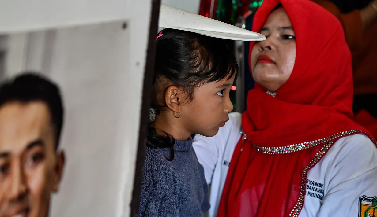 Seorang petugas kesehatan mengukur tinggi balita dalam program pemeriksaan kesehatan bulanan untuk anak-anak di sebuah pusat layanan terpadu di Banda Aceh, Senin,  10 Agustus 2026. (AFP/ Chaideer Mahyuddin)