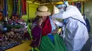 Seorang petugas kesehatan menginokulasi seorang perempuan dengan vaksin COVID-19 Sinopharm, di pulau Uro di danau Titicaca di Puno, Peru, pada 7 Juli 2021. Peru memulai vaksinasi COVID-19 untuk ratusan penduduk asli yang tinggal di pulau terapung Uros, di Danau Titicaca. (Carlos MAMANI / AFP)