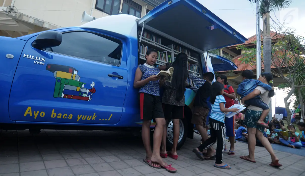 Sejumlah anak membaca buku di mobil Perpustakaan Keliling di Klungkung, Bali, Sabtu (30/09). Mobil Perpustakaan Keliling ini mulai buka pada pukul 16.00 hingga 21.00 dan menyediakan ratusan buku bacaan. (Liputan6.com/Gempur M Surya)