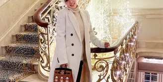 Topi putih dan loang coat berwarna senada akan membuatmu tampil bak ratu kerajaan.&nbsp;(instagram/princesssyahrini)