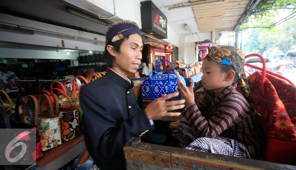 PKL bermain dengan seorang anak di emperan toko kawasan Malioboro mengenakan pakaian tradisional, Rabu (20/4/2016). Sejumlah PKL mengenakan pakain adat jawa menyambut hari Kartini 21 April besok. (Liputan6.com/Boy Harjanto)