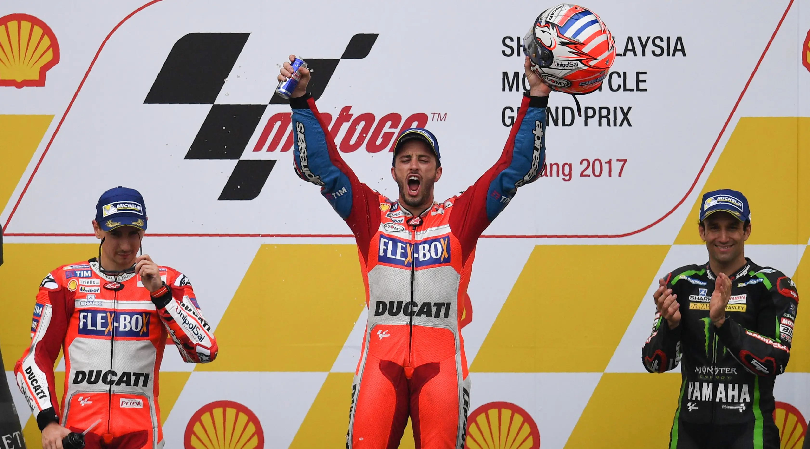  Pembalap Ducati Team, Andrea Dovizioso mengangkat helmnya bersama Jorge Lorenzo dan Johann Zarco di atas podium setelah memenangkan MotoGP Malaysia di sirkuit Sepang.  (Manan VATSYAYANA / AFP)