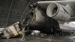Prajurit Ukraina melewati pesawat Antonov An-225 Mriya yang hancur di bandara Antonov, Hostomel, 2 April 2022. Di pintu masuk Bandara Antonov, pasukan menjaga posisinya, tanda mereka memegang kendali penuh atas landasan pacu yang coba diserbu Rusia di hari-hari pertama perang (AP Photo/Vadim Ghirda)