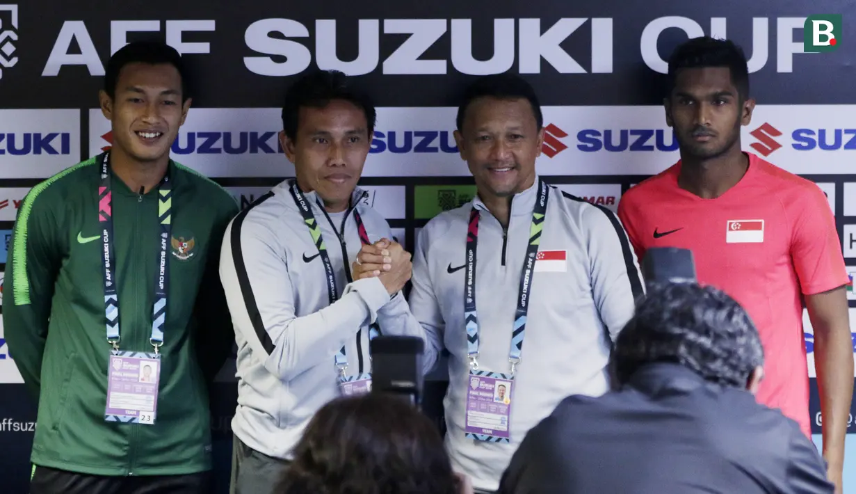 Pelatih Timnas Indonesia, Bima Sakti dan pelatih Singapura, Fandi Ahmad, bersalaman saat jumpa pers jelang laga Piala AFF 2018 di Stadion Nasional, Singapura, Kamis (8/11). Timnas akan berhadapan dengan Singapura. (Bola.com/M. Iqbal Ichsan)