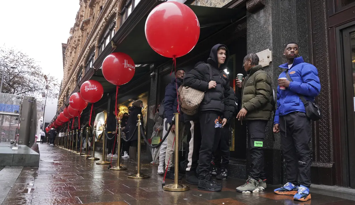 Pembeli mengantre di tengah hujan untuk memulai penjualan 'Boxing Day' di department store di Knightsbridge, London, Minggu (26/12/2021).  'Boxing Day' adalah hari saat toko-toko di Inggris menggelar diskon besar-besaran, sehari setelah Natal. (Jonathan Brady/PA via AP)