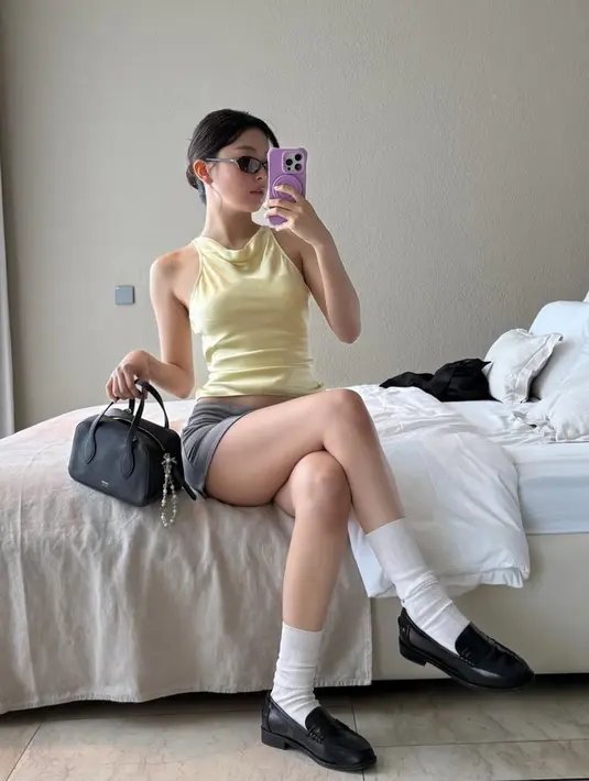 Seulgi pun memerlihatkan ootdnya selama di Bali. Misalnya mengenakan atasan sleeveless 
butter yellow dipadukan mini skirt abu-abu. Lalu kaos kaki panjang putih di atas sepatu leofer hitam yang serasi dengan warna mini handbagnya. [@hi_sseulgi]