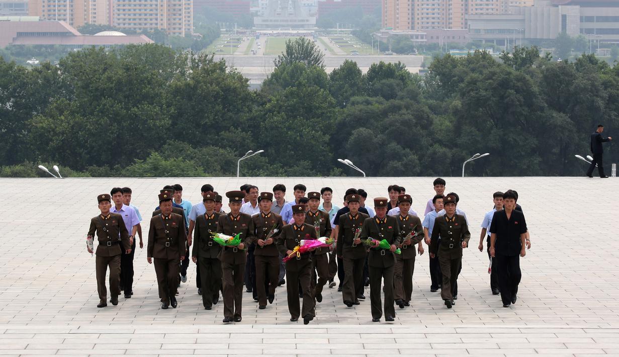 Tentara membawa bunga saat akan memberi penghormatan kepada patung pemimpin Korea Utara Kim Il Sung dan Kim Jong Il dalam peringatan berakhirnya Perang Dunia II dan pembebasan dari kolonial Jepang di Pyongyang, Korut, Rabu (15/8). (AP Photo/Ng Han Guan)