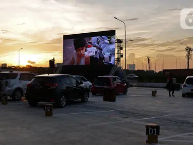 Deretan mobil penonton terparkir saat menyaksikan pemutaran film secara drive-in di Cikarang, Bekasi, Jawa Barat, Rabu (3/6/2020). Kehadiran drive-in cinema memberikan hiburan alternatif kepada warga di tengah pandemi virus corona COVID-19. (Liputan6.com/Herman Zakharia)