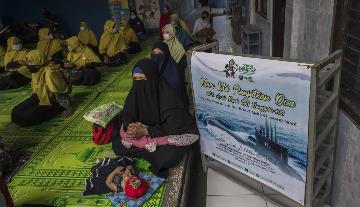Siswa dan guru berdoa untuk 53 awak kapal selam KRI Nanggala 402 yang hilang hilang kontak, di sebuah sekolah Islam di Surabaya, Jumat (24/4/2021). Kapal selam KRI Nanggala-402 hilang kontak saat sedang melaksanakan latihan penembakan dengan torpedo di perairan utara Pulau Bali. (Juni Kriswanto/AFP)
