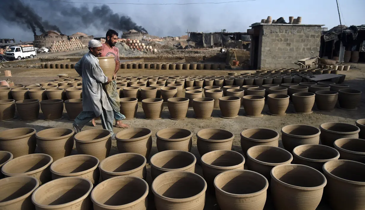 Pembuat tembikar menempatkan pot tanah liat untuk dikeringkan di sebuah bengkel di Karachi, Pakistan, Rabu (23/2/2022). (Rizwan TABASSUM/AFP)