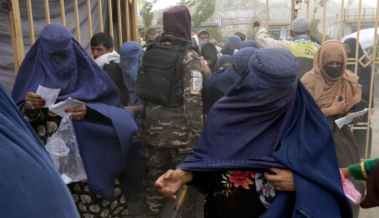 <p>Seorang Taliban berjalan di antara orang-orang yang menunggu untuk menerima jatah makanan yang didistribusikan oleh kelompok bantuan kemanusiaan Korea Selatan, di Kabul, Afghanistan, Selasa (10/5/2022). Taliban pada Sabtu pekan lalu memerintahkan semua perempuan Afghanistan menutupi seluruh tubuhnya atau mengenakan burqa tradisional di depan umum. (AP Photo/Ebrahim Noroozi)</p>