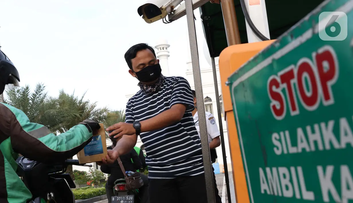 Petugas membagikan takjil dengan sistem drive thru di Masjid Agung Al-Azhar, Jakarta, Selasa (5/5/2020). Selama Ramadan, pengurus Masjid Agung Al-Azhar membagikan 300 takjil per hari buat pengendara yang melintasi lokasi tersebut. (Liputan6.com/Helmi Fithriansyah)
