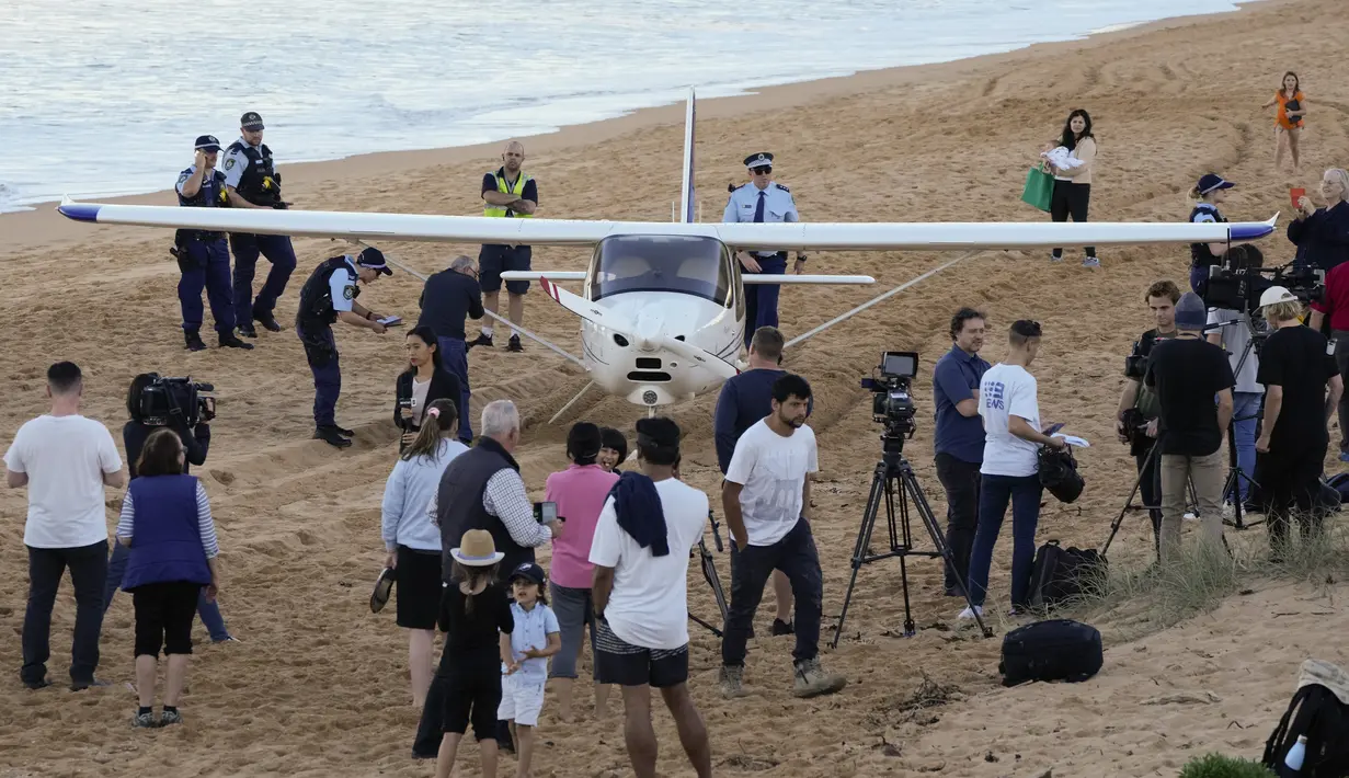 Orang-orang berdiri di dekat sebuah pesawat ringan yang mendarat darurat di sebuah pantai di Sydney, Rabu (26/5/2021). Pesawat kategori rekreasi itu mendarat selamat di pantai Sydney dengan tiga orang di dalamnya termasuk seorang bayi setelah mengalami kerusakan mesin. (AP Photo/Mark Baker)