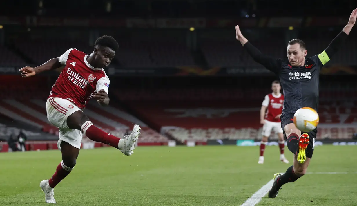 Striker Arsenal, Bukayo Saka (kiri) melepaskan umpan yang coba dihalangi bek Slavia Praha, Jan Boril dalam laga leg pertama perempatfinal Liga Europa 2020/2021 di Emirates Stadium, London, Kamis (8/4/2021). Arsenal bermain imbang 1-1 dengan Slavia Praha. (AP/Alastair Grant)